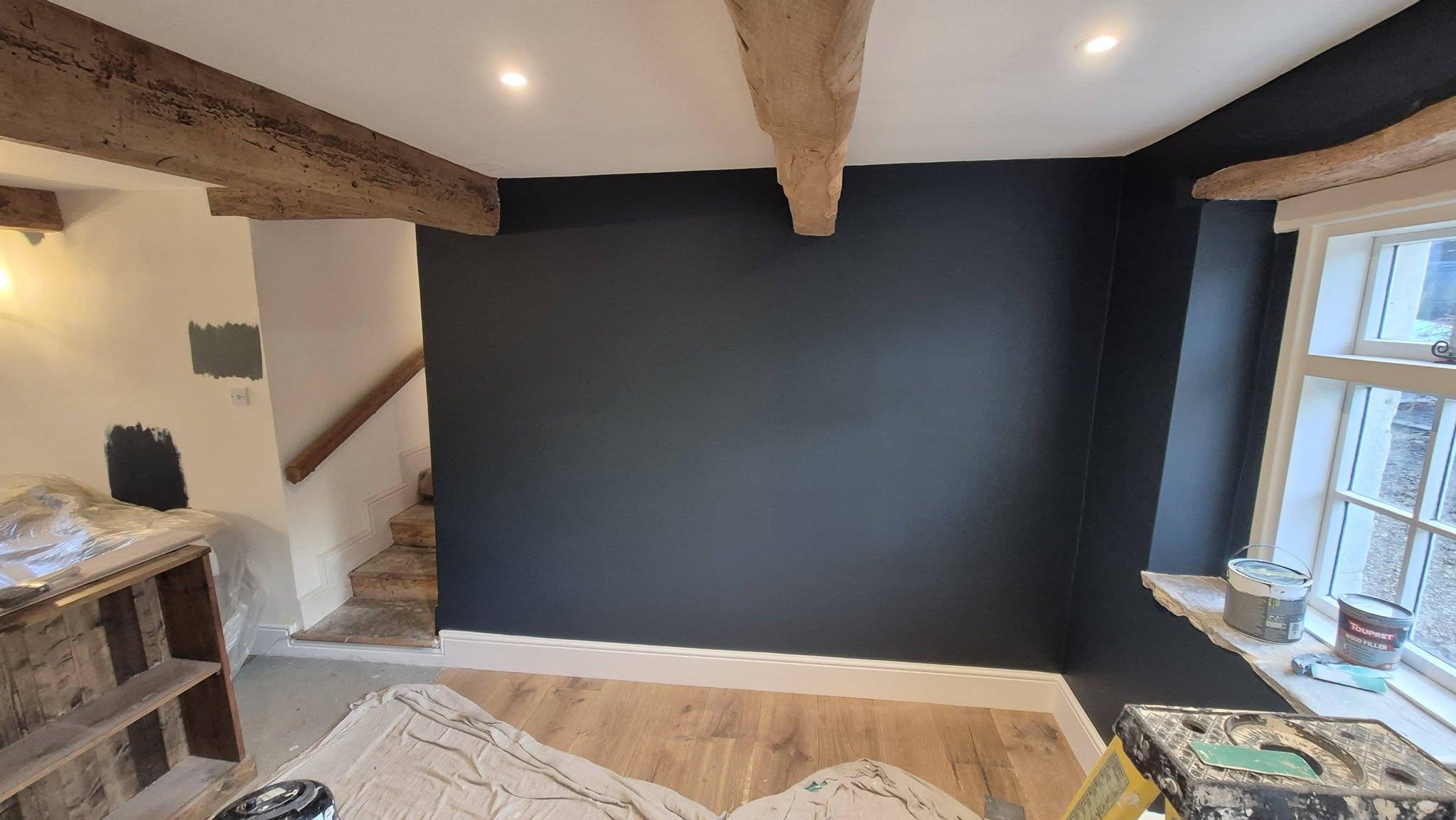 Living room with dark navy feature wall, exposed oak beams and white painted woodwork