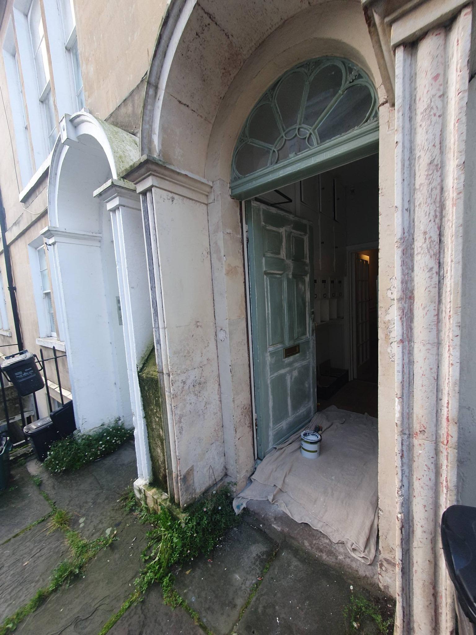Georgian stone entrance arch with fanlight window and door being prepared for painting in Bath