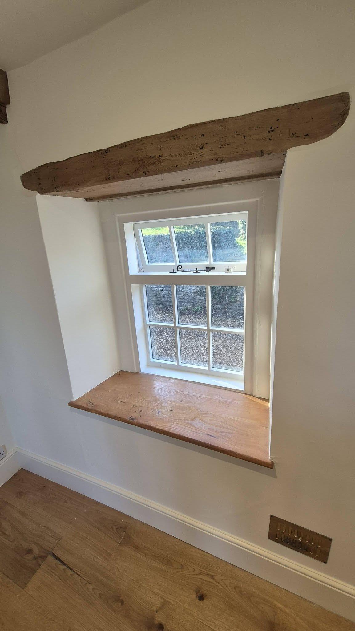 Period cottage window with white painted reveal, oak lintel beam and wooden windowsill