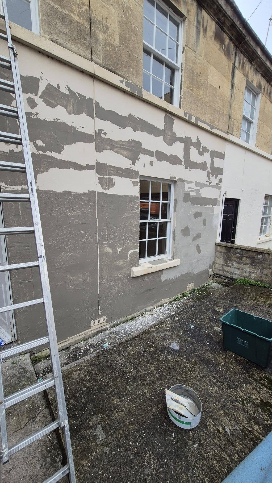 Exterior wall preparation with scraping, filling and ladder against Bath stone property