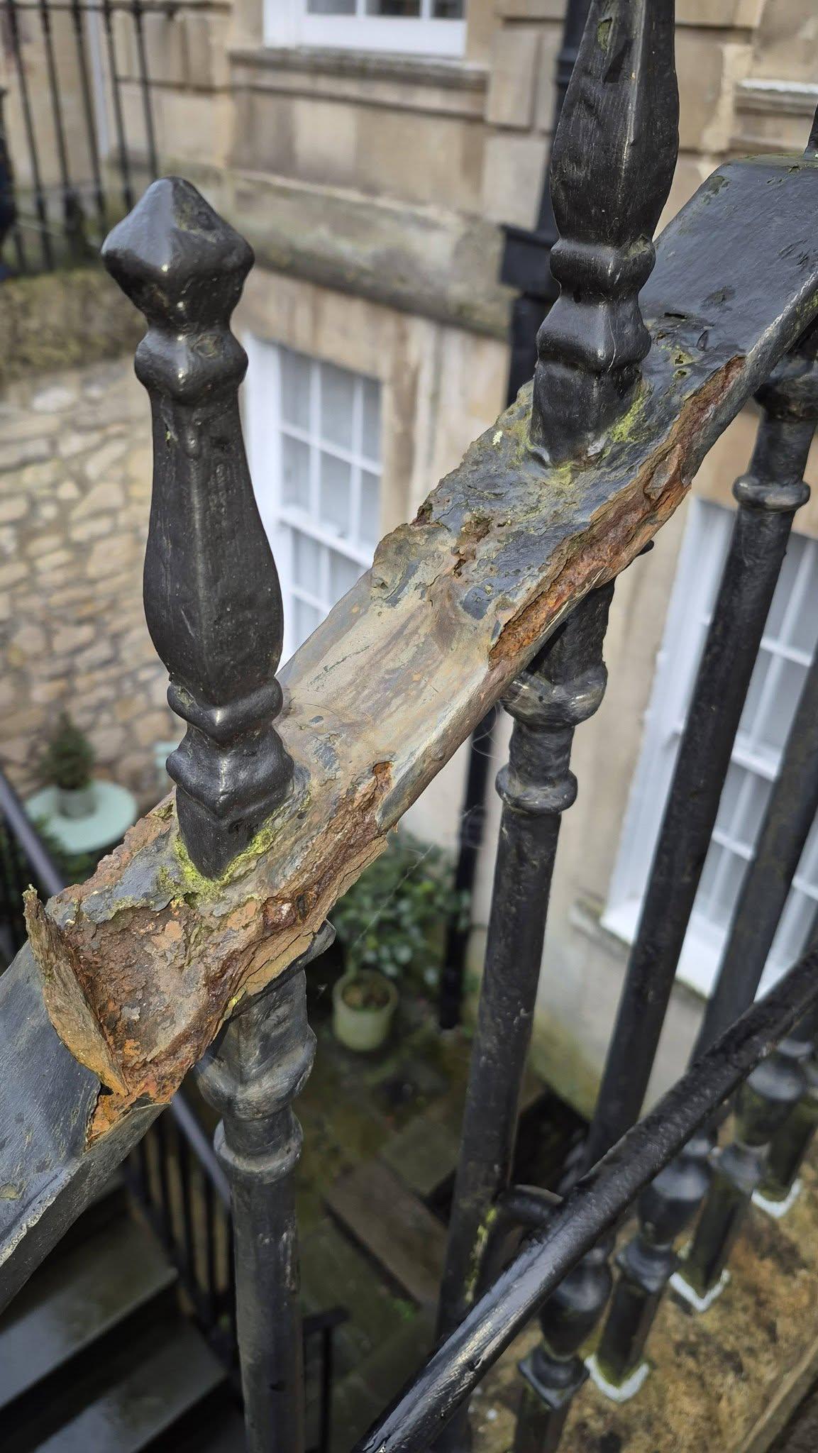 Weathered wrought iron railings in Bath before restoration — rust, flaking paint and moss