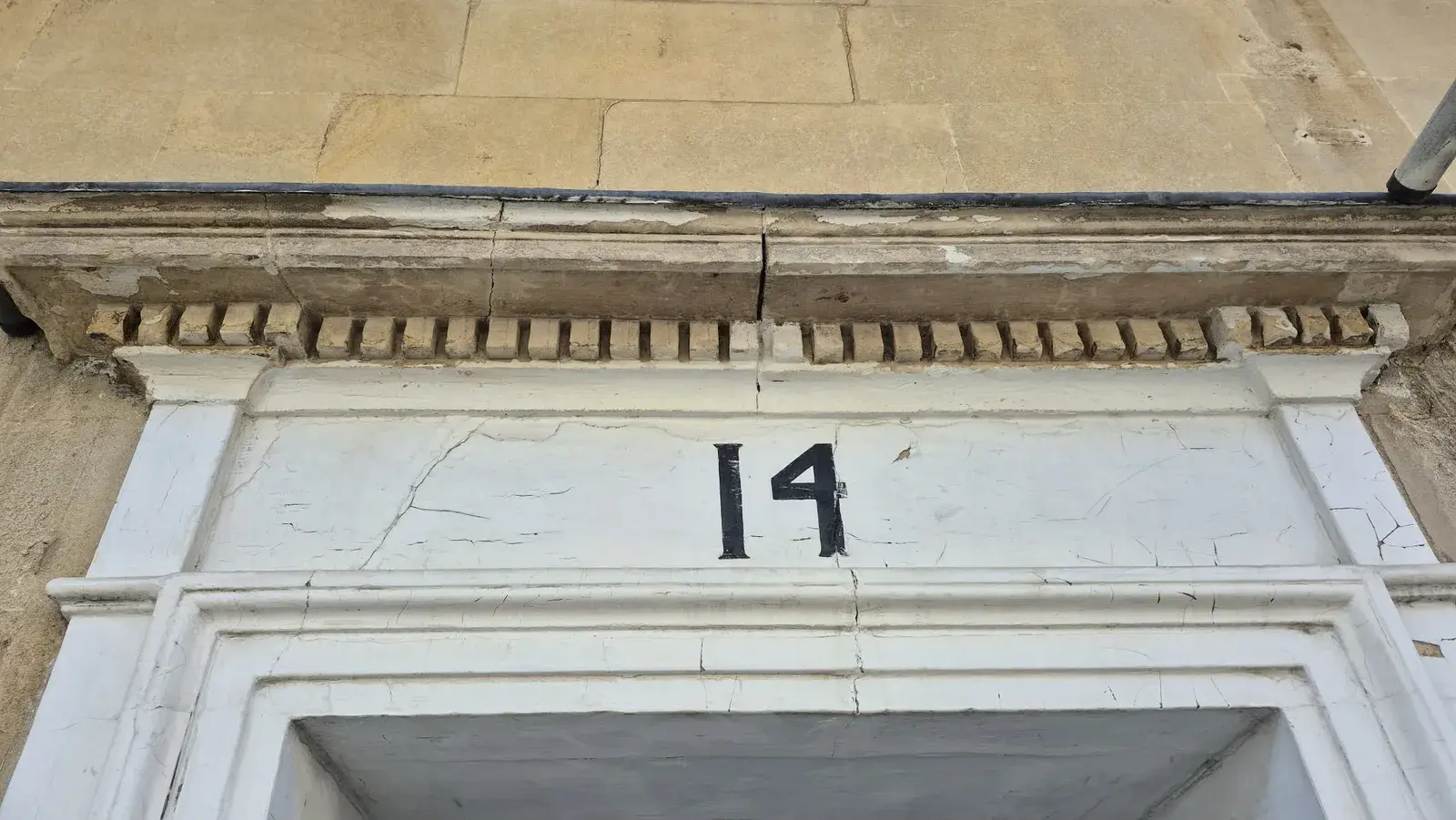 Cracked, blown paint on the dentil cornice and door head before preparation, Bath