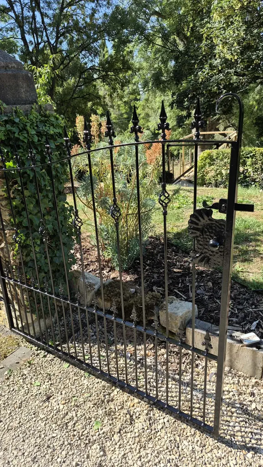 Wrought iron gate with fleur-de-lis finials repainted in black gloss