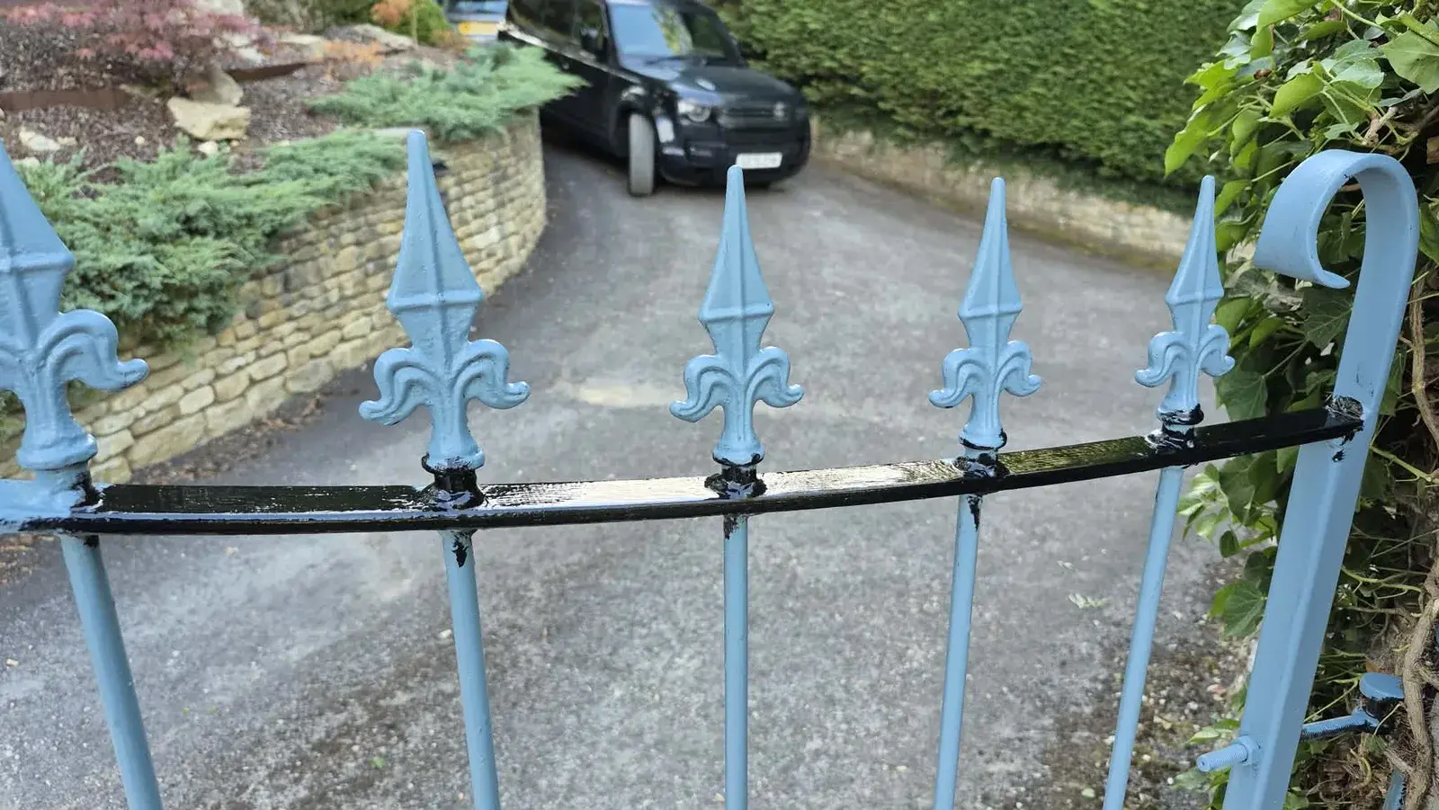 Wrought iron gate part-painted, black topcoat going on over blue rust-inhibiting primer